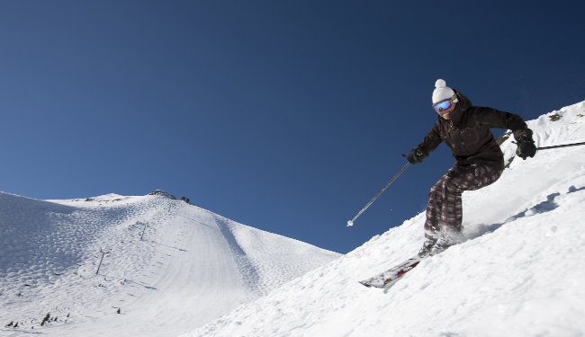 View of a skier skiing down snow covered mountains.