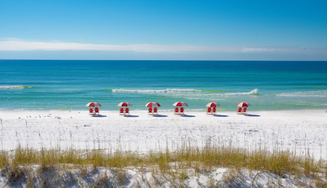 Looking out towards the white sand beach and ocean with umbrellas in the sand.