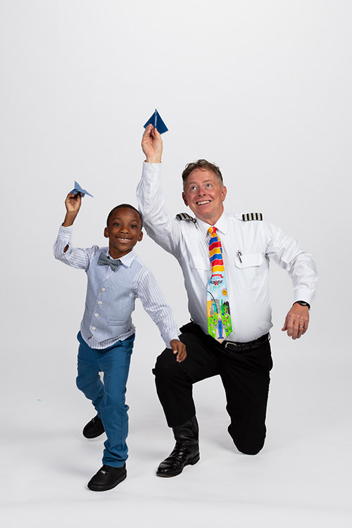 Southwest pilot and a young student smiling and holding paper airplanes